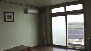 A room with a large sliding glass door, a ceiling light, and a framed picture on the wall. - Il Sung Jeju Beach Resort (Jeju City)