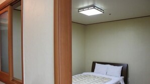 A bedroom with a bed, a window, and a ceiling light. - Il Sung Jeju Beach Resort (Jeju City)