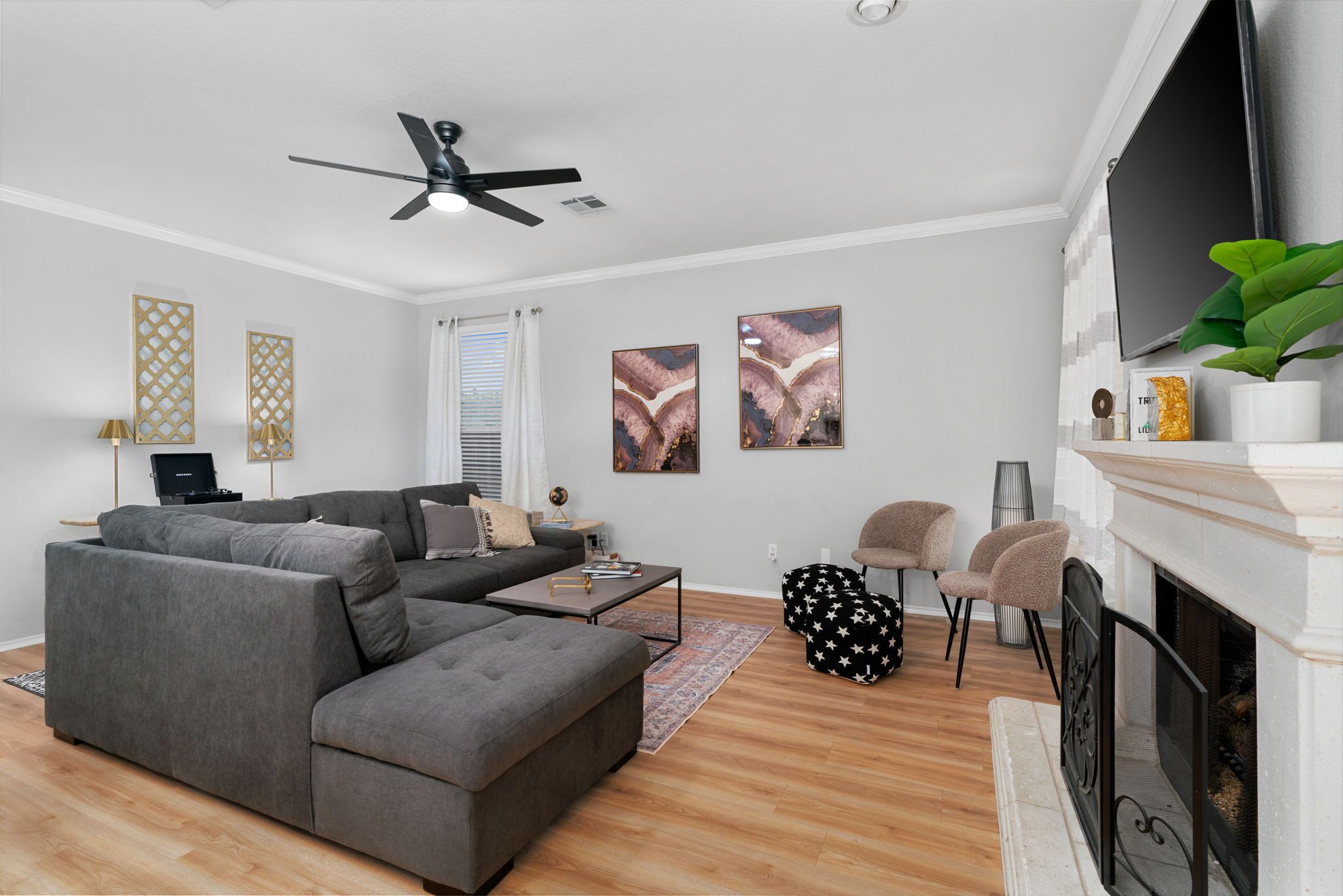 A modern living room with a sectional sofa, a fireplace, and a ceiling fan.