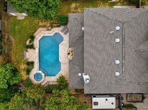 An aerial view of a residential property with a swimming pool, a covered patio, and a large house with a tiled roof. - Incredible Heated Pool Tub Gameroom  (Pflugerville)