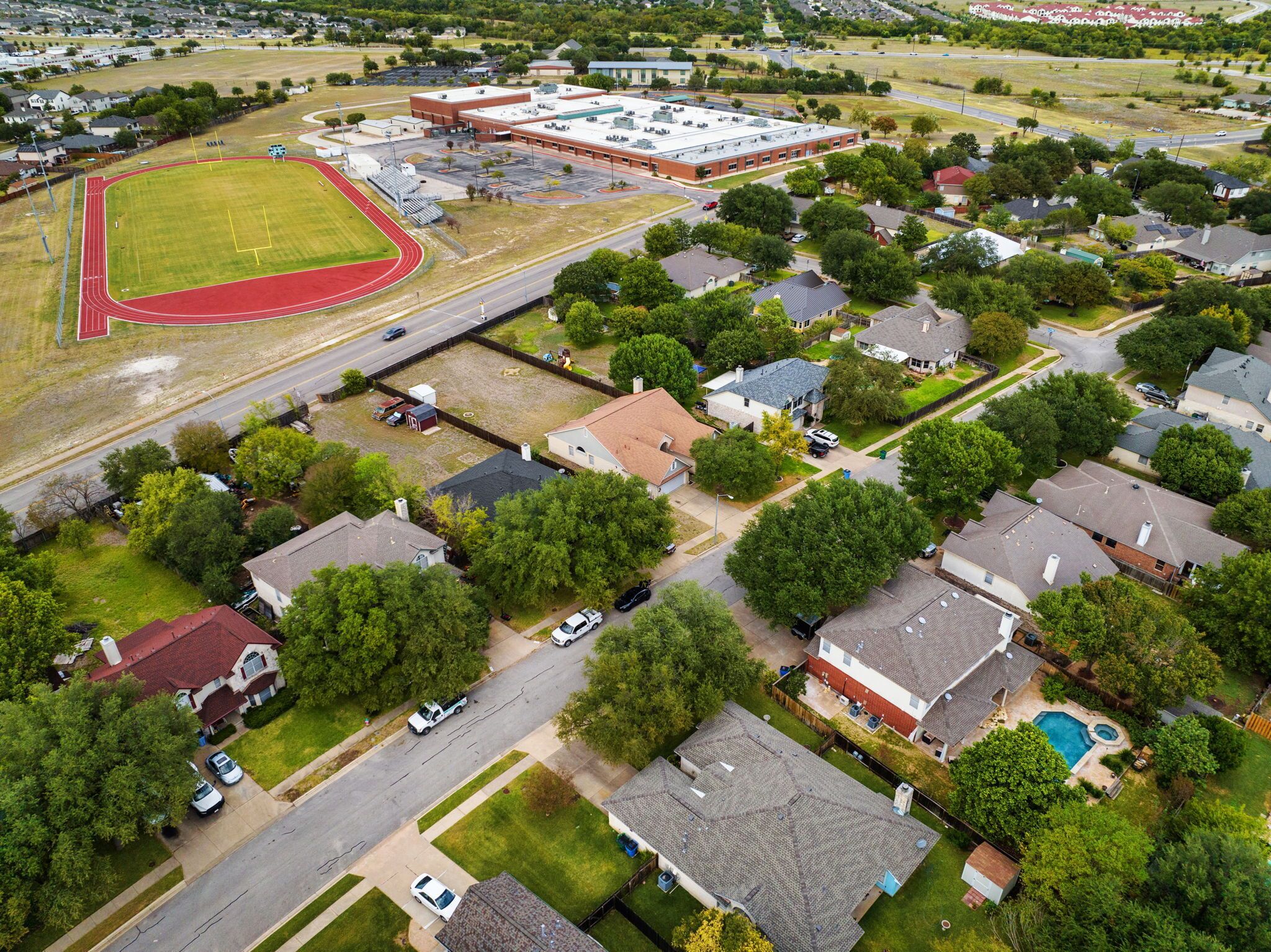 An aerial view of a residential area with houses, a school building, and a sports field.