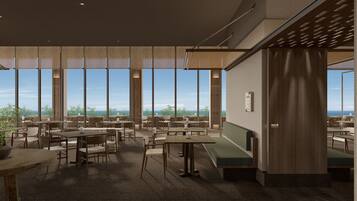A spacious indoor dining area with high ceilings and large windows offering a view of the outdoors. Tables and chairs are arranged for dining, and a green cushioned bench is visible.