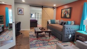 Una sala de estar con sofá, sillón, mesa de centro y alfombra estampada.