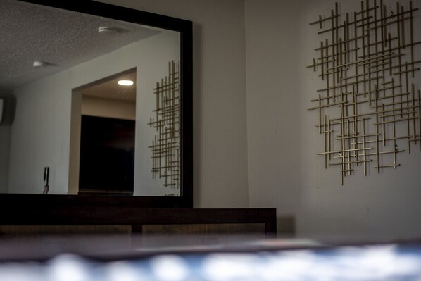 A bathroom with a mirror, a wooden bench, and a wall-mounted light fixture.