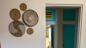 Quarto com uma poltrona de couro marrom, uma obra de arte tecida na parede e uma porta verde-água com sinal de alerta.