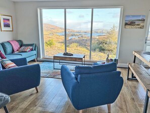 Un salon moderne avec une grande fenêtre, un canapé bleu, une table basse et un banc en bois.