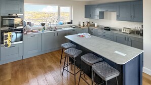 Una cocina moderna con armarios grises, una isla grande con taburetes y vistas a un paisaje desértico a través del ventanal.