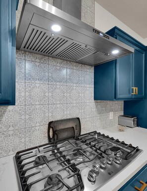 Une cuisine équipée d’une cuisinière à gaz, d’un grille-pain et de meubles de couleur bleue.