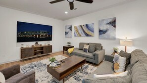 Een moderne woonkamer met een flatscreen televisie, een bank, een salontafel en kunstwerken aan de wanden.