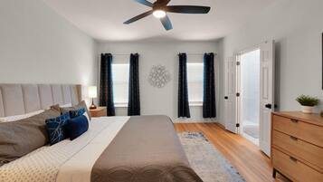 A bedroom with a bed, nightstands, a dresser, a ceiling fan, and a wall decoration.