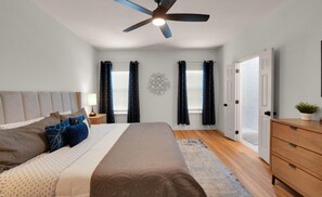 A bedroom with a bed, nightstands, a dresser, a ceiling fan, and a wall decoration. - Game Room | Near Downtown | Silos and More (Waco)