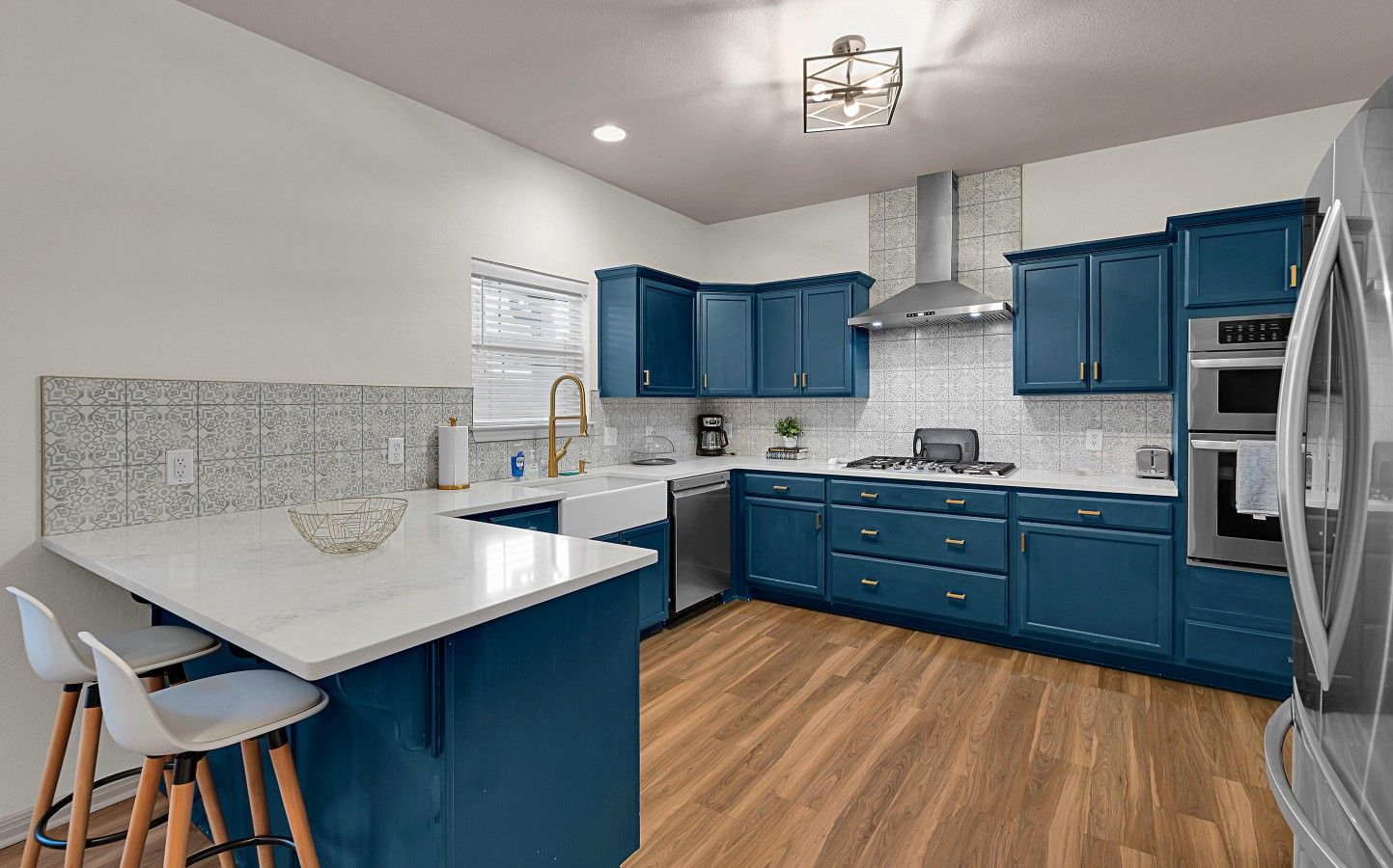 Una cocina moderna con armarios azules, una encimera blanca y un refrigerador de acero inoxidable.