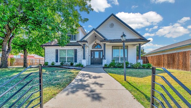 A two-story house with a front entrance, a covered porch, and a driveway leading to the front door. - Game Room | Near Downtown | Silos and More (Waco)