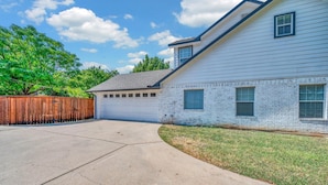 A residential house with a garage, a driveway, and a wooden fence. - Game Room | Near Downtown | Silos and More (Waco)