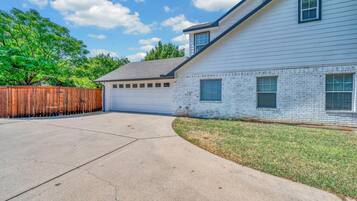 A residential house with a garage, a driveway, and a wooden fence.