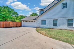 A residential house with a garage, a driveway, and a wooden fence. - Game Room | Near Downtown | Silos and More (Waco)