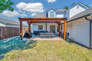 A backyard patio with a pergola, outdoor furniture, and a barbecue grill.