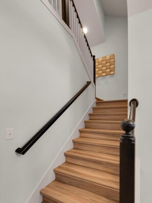 A wooden staircase with a black handrail and a wall-mounted light fixture.