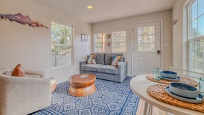 A spacious living room with a gray sofa, a round wooden coffee table, and a blue patterned rug. - Pet Friendly | Dog Run | New Remodel | Wildlife (Alto)