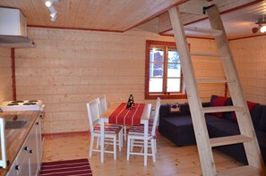 Ein gemütliches Blockhauss-Interieur mit Essbereich, einer Couch, einer Leiter und einem Fenster.