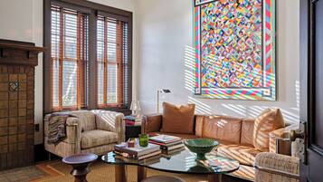 Una sala de estar acogedora con chimenea, un ventanal con persianas, un colcha de colores y un área de descanso confortable.