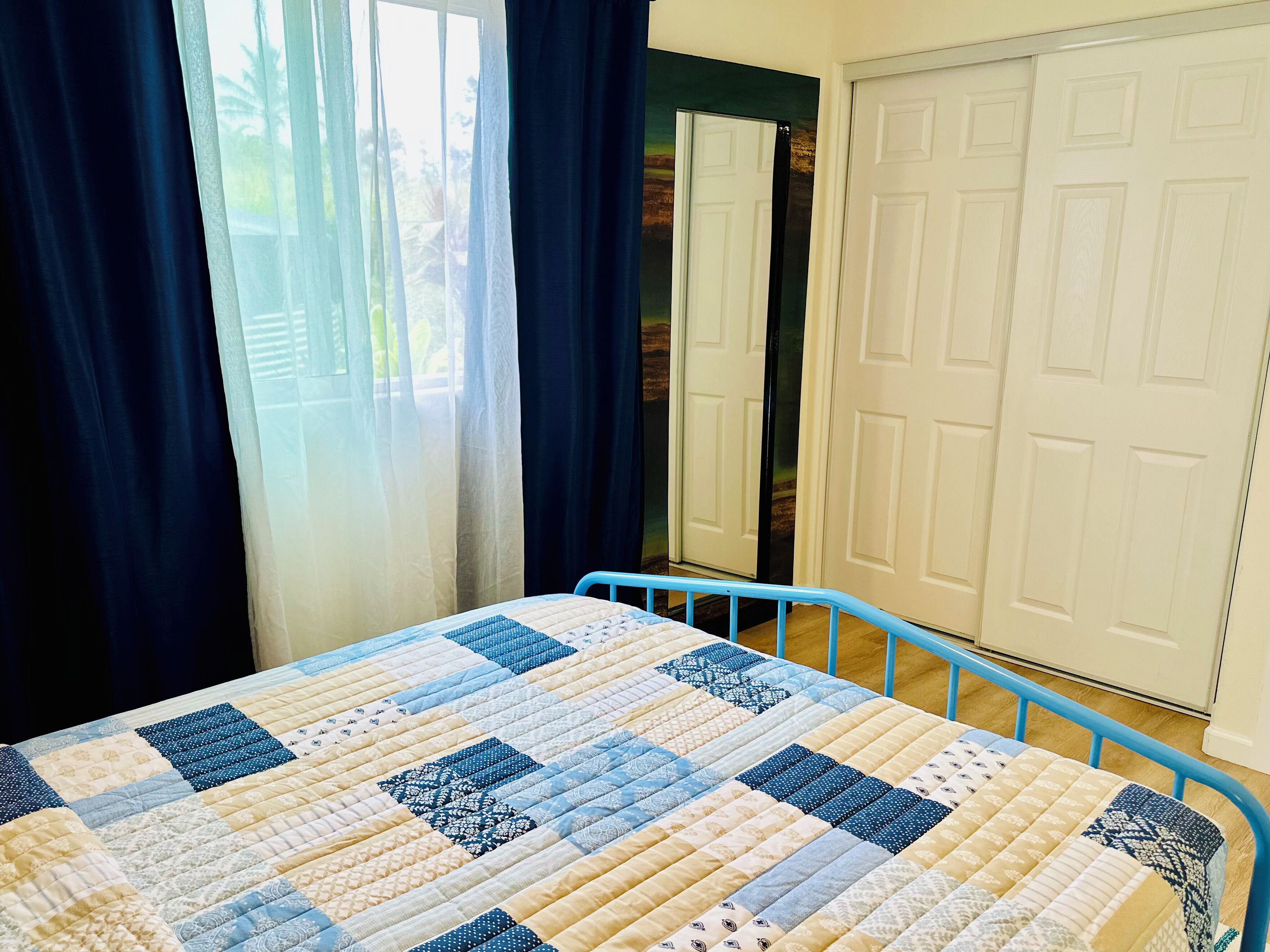 A bedroom with a bed, a window with curtains, and a door.