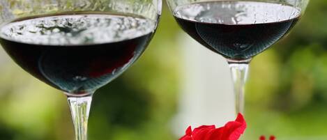 Dos copas de vino sobre una mesa con una flor roja.