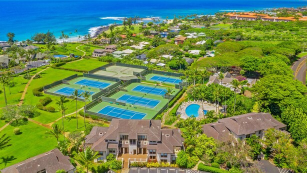 Een woongebied met meerdere tennisbanen, een zwembad en huizen met uitzicht op de oceaan.