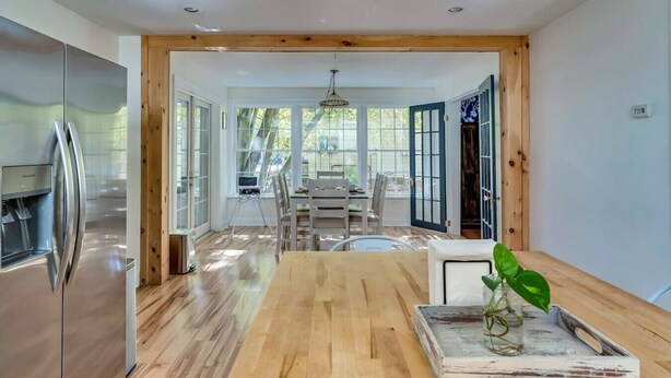 A modern kitchen with a stainless steel refrigerator, wooden flooring, and a dining area with a table and chairs. - Pool Table & More Spacious Family Fun (Canton)