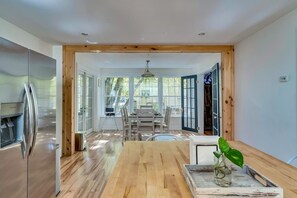 A modern kitchen with a stainless steel refrigerator, wooden flooring, and a dining area with a table and chairs.