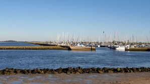 Un port de plaisance où sont amarrés de nombreux voiliers, une côte rocheuse et un ciel bleu dégagé.