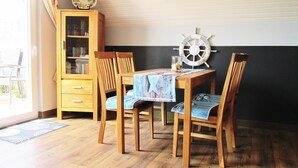 Un coin repas avec une table et des chaises en bois, une décoration en forme de roue de navire et un meuble avec des portes en verre.