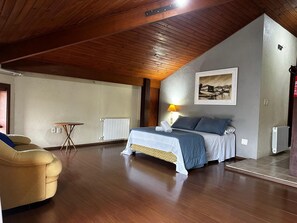Un dormitorio con una cama, una silla, una mesa y un radiador.