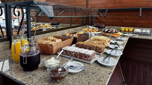 A buffet with various food items, including bread, pastries, and desserts. - Pousada Canela Garden (Canela)