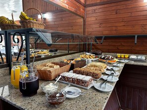 A buffet with various food items, including bread, pastries, and desserts. - Pousada Canela Garden (Canela)