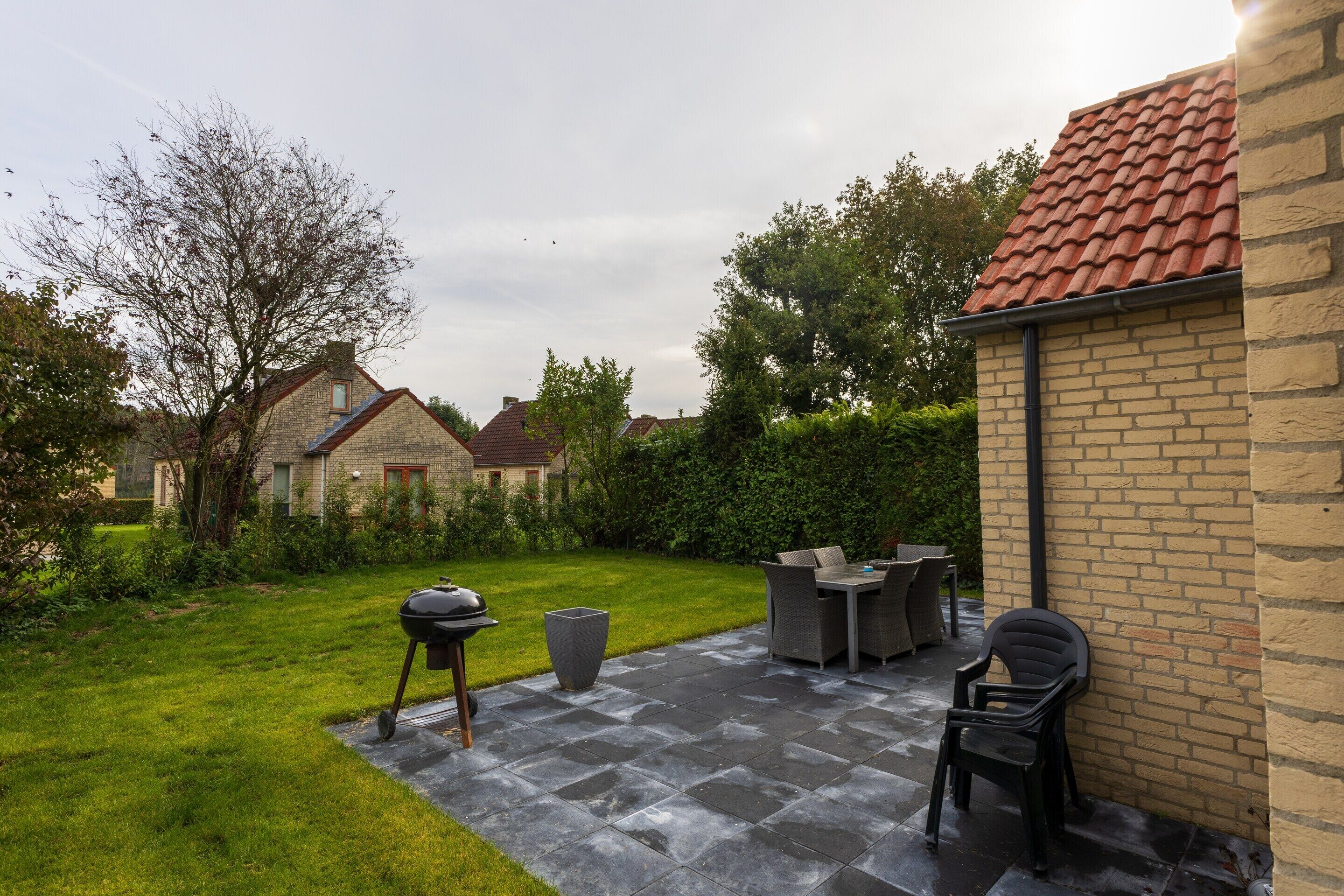 Un espace patio aménagé avec un barbecue, du mobilier d’extérieur et un mur en briques.