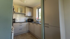 Une cuisine avec des meubles blancs, un four à micro-ondes et une fenêtre donnant sur un beau paysage.