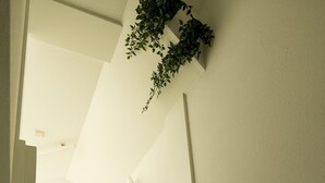 A white staircase with a handrail, a plant on the wall, and a light fixture. - Holiday Home in Ewijk in a Beautiful Area (Ewijk)