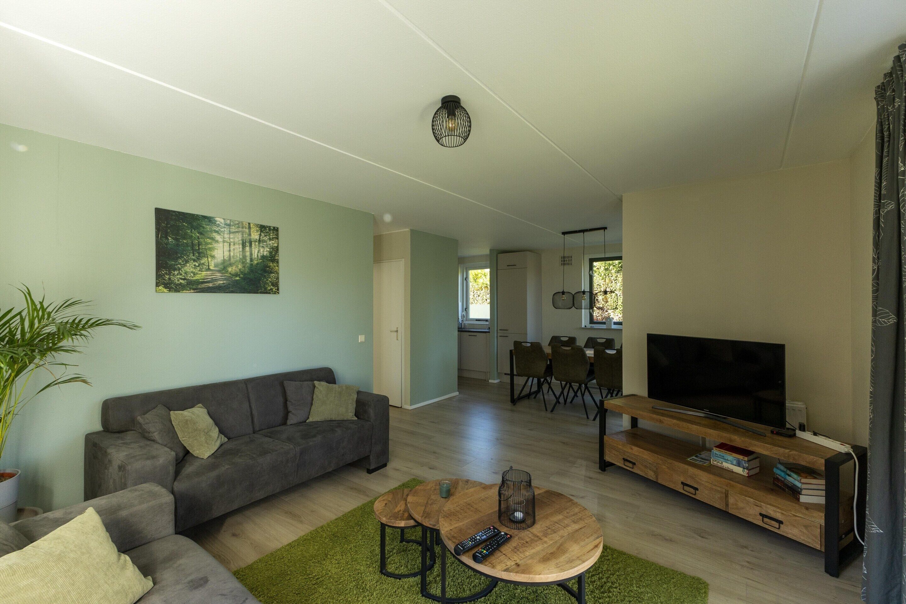 A modern living room with a grey sofa, a wooden coffee table, and a TV on a wooden stand.