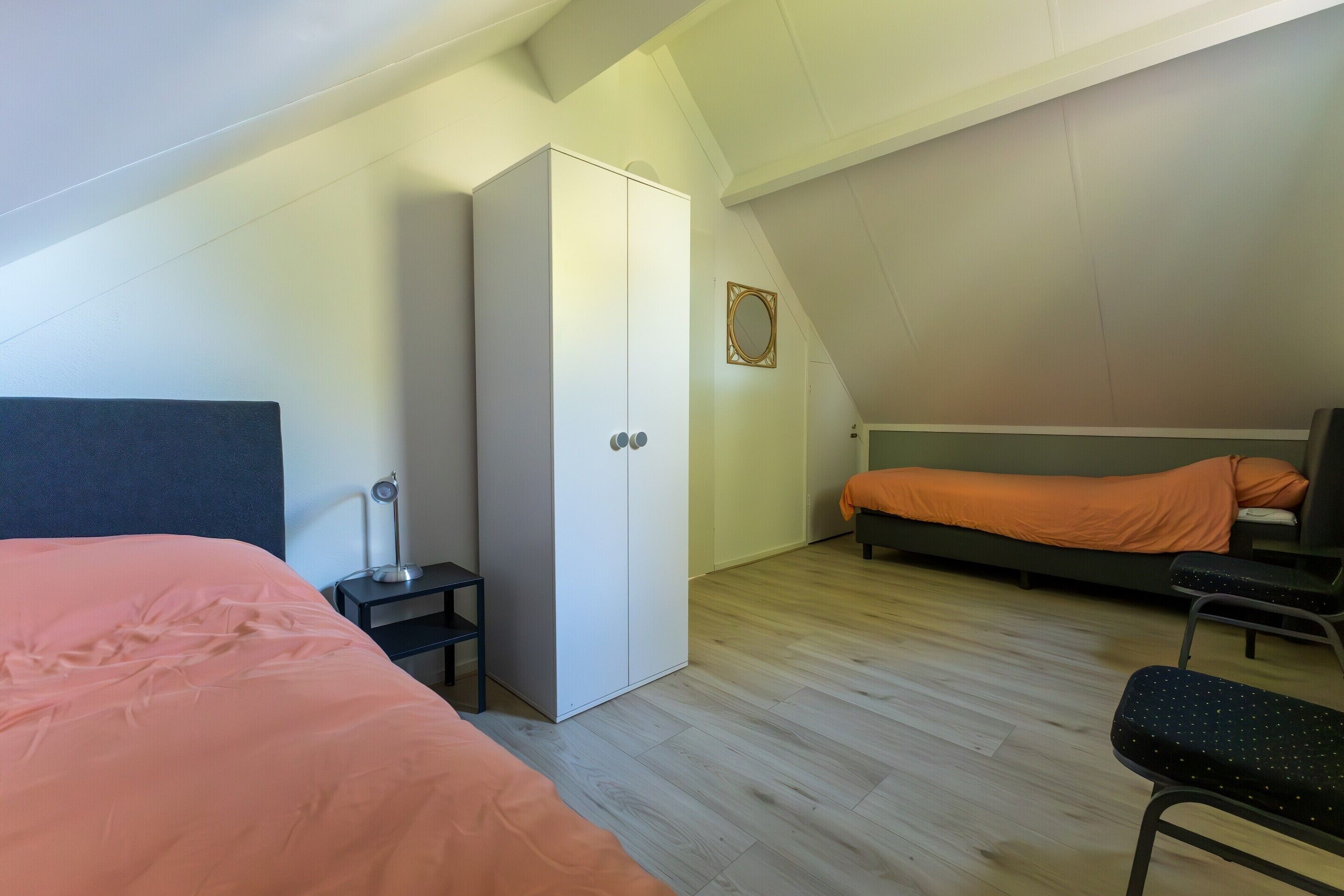A bedroom with a bed, a wardrobe, a desk, and a chair.