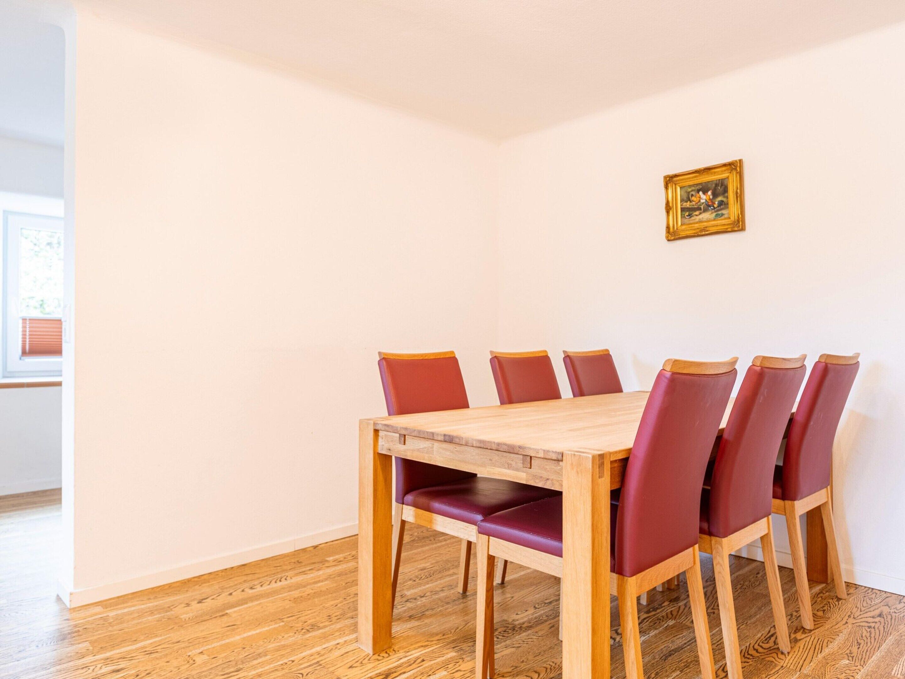 Un comedor con una mesa de madera y seis sillas rojas.