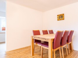 Un comedor con una mesa de madera y seis sillas rojas.