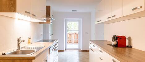 Una cocina moderna con una isla central, pileta de acero inoxidable y alacenas de madera.