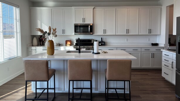 A modern kitchen with white cabinets, a central island with bar stools, a microwave, and a stove. -  Beautiful home near Thanksgiving Point. Views of Utah Lake, sunrise and sunset (American Fork)