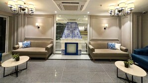 A modern hotel lobby with two sofas, a patterned floor, and a decorative blue tile wall. - Meritas Auberge Calangute Goa (Calangute)