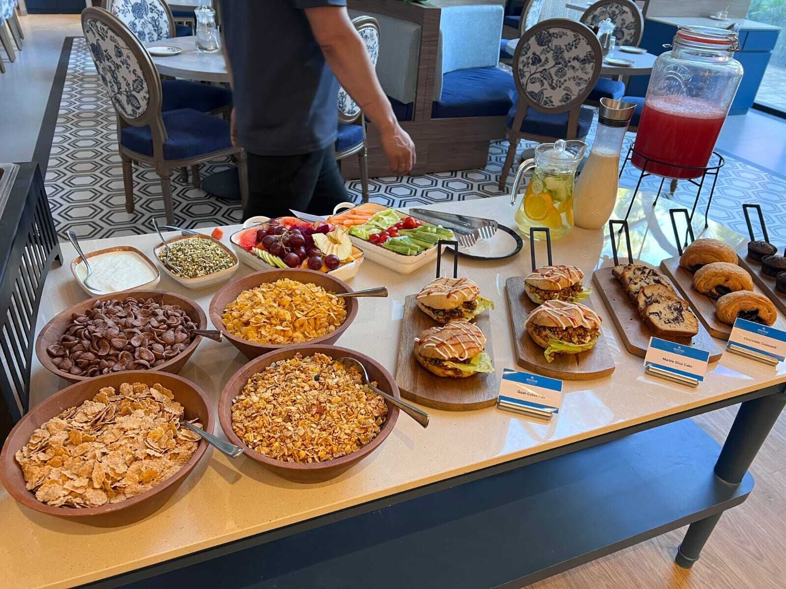 Un bufé con una variedad de alimentos, como cereales, frutas, sándwiches y pasteles.