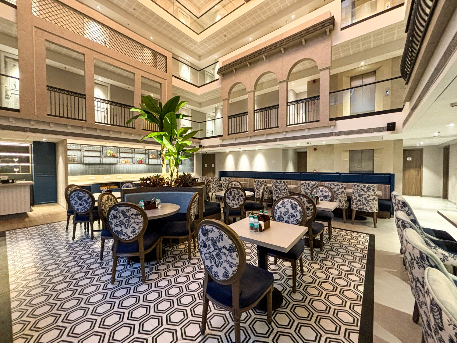 Un vaste espace de restauration intérieur doté de hauts plafonds, de plusieurs niveaux et d’un espace central avec des tables et des chaises.