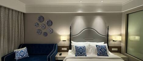 Una habitación de hotel con una cama, un sofá azul, una mesita de noche con una lámpara y una pared decorada con platos.