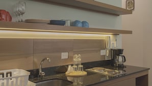 A modern kitchen with a built-in sink, a coffee maker, and a shelf with plates and glasses. - Estudio LALO Temozon Norte Mérida (Mérida)