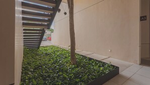 A modern building with a minimalist design, featuring a tree and green plants in a planter, a sloped ceiling, and a sign indicating room A3. - Estudio LALO Temozon Norte Mérida (Mérida)